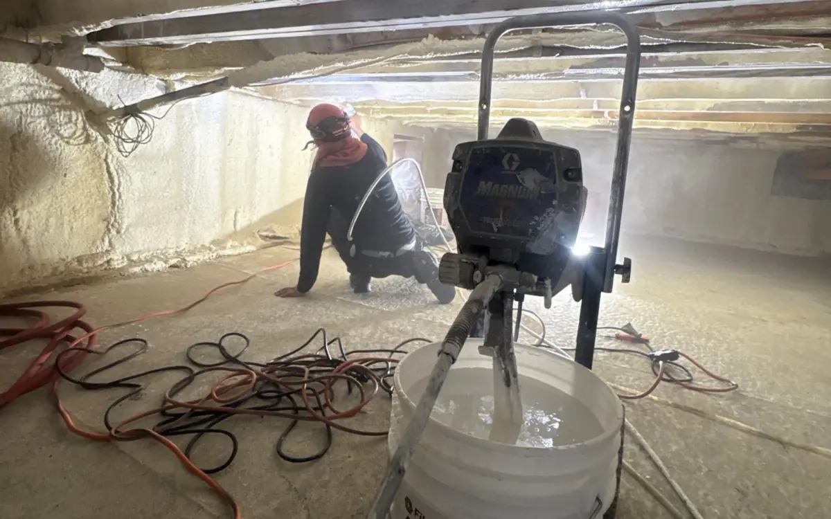 K.O.S. technician spraying encapsulant across a Hamptons crawlspace