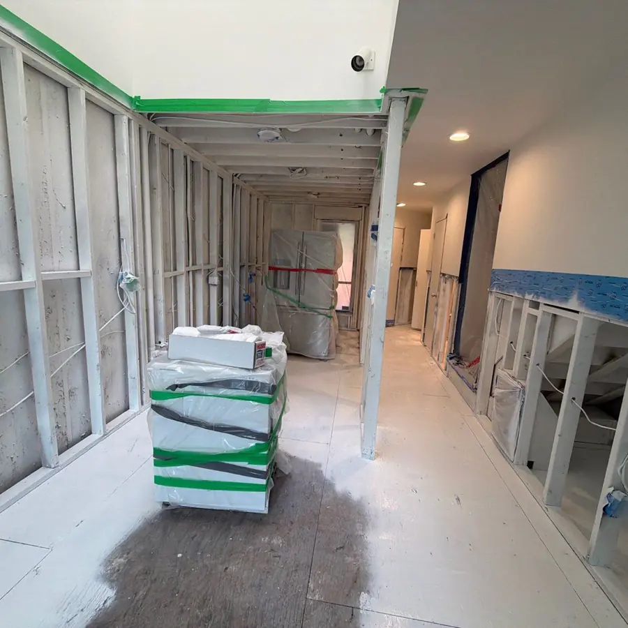 Encapsulation in progress along a downstairs hallway, finishes masked