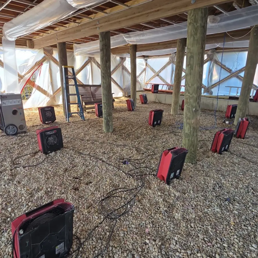 Air movers set out across a crawlspace under a Mastic Beach home