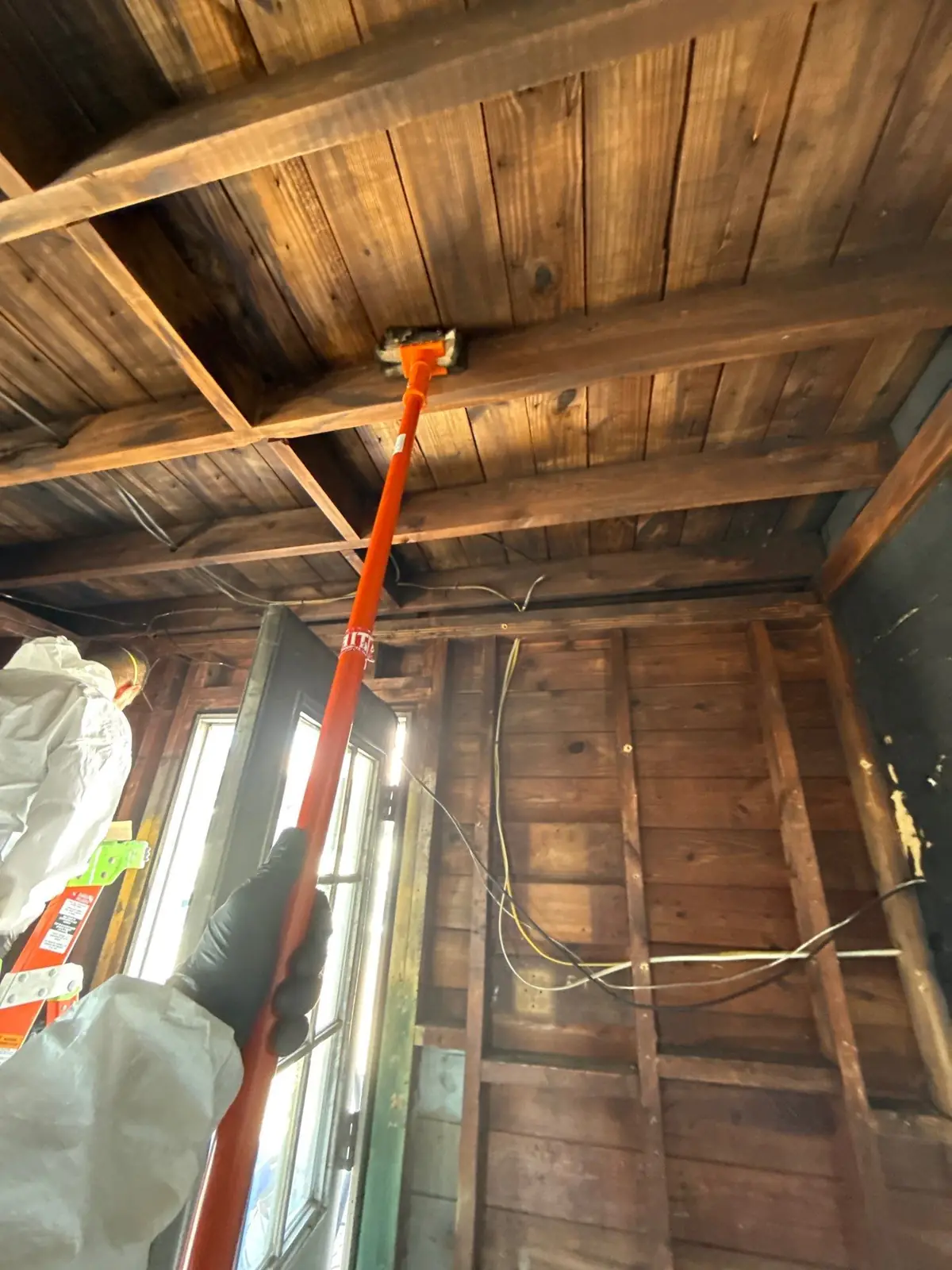 Crew scrubbing soot from the ceiling boards with a pole-mounted pad
