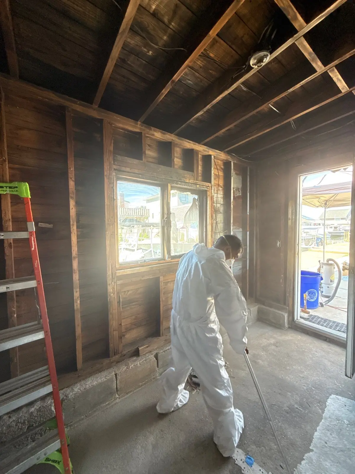 K.O.S. technician in a full protective suit working the floor of a fire-damaged room