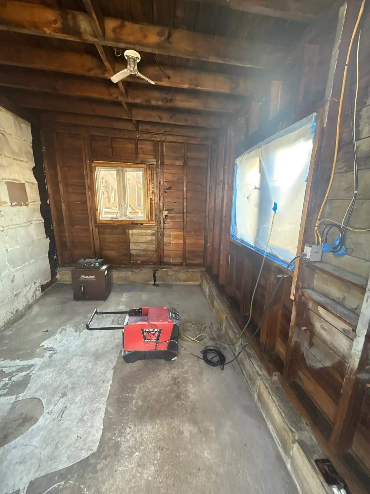 Fire-damaged room stripped to the framing, windows sealed and air equipment running