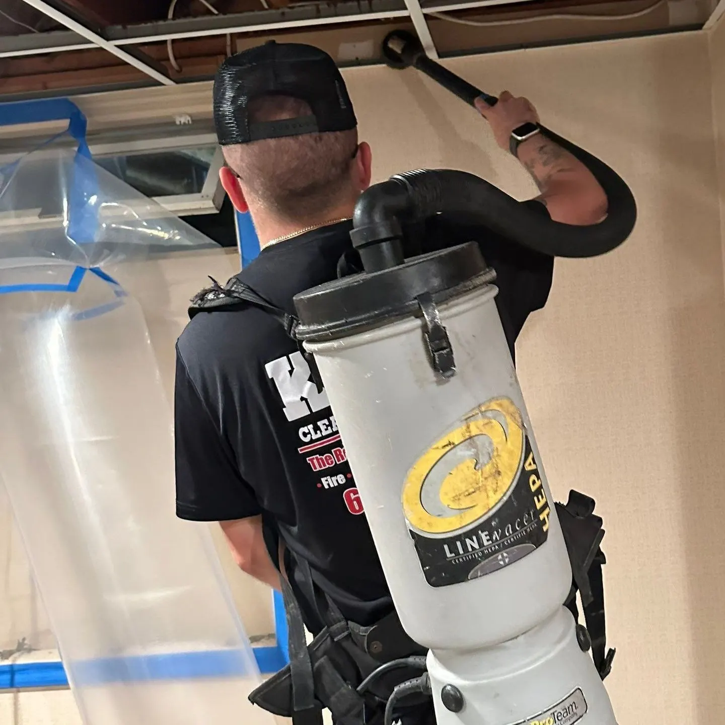 K.O.S. technician HEPA-vacuuming a ceiling inside mold containment in Setauket