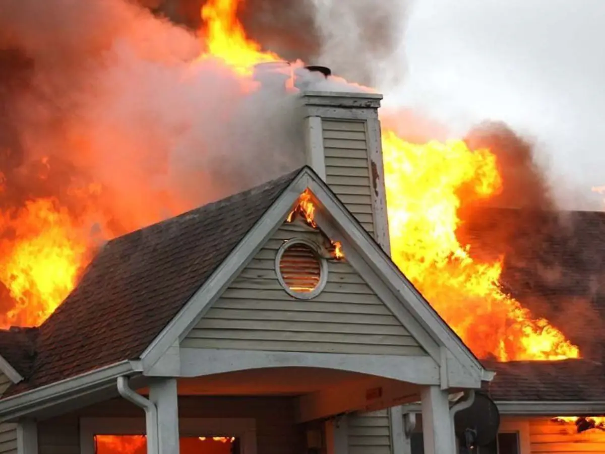 House engulfed in flames with heavy smoke pouring from the roof