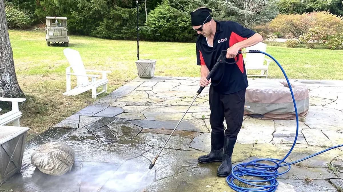 K.O.S. technician pressure-washing a stone patio