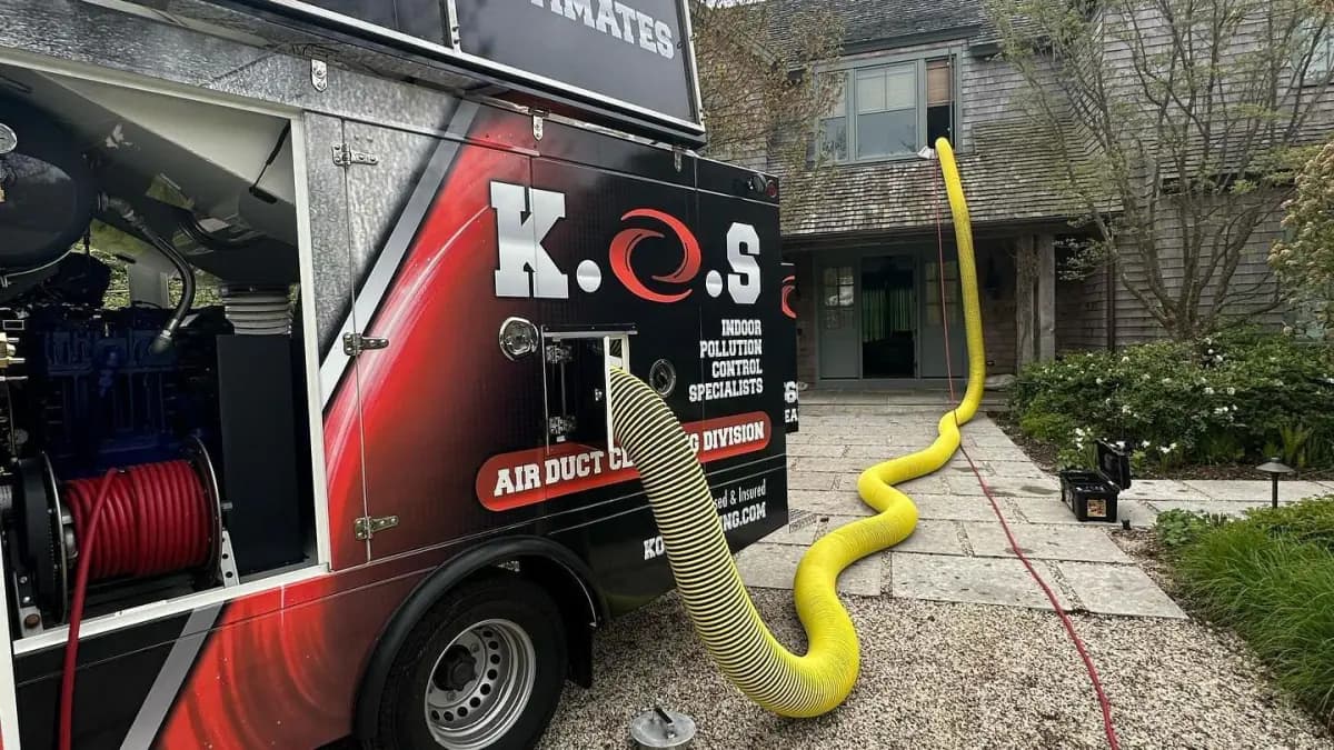 a red and black truck with a yellow hose attached to it is parked in front of a house .