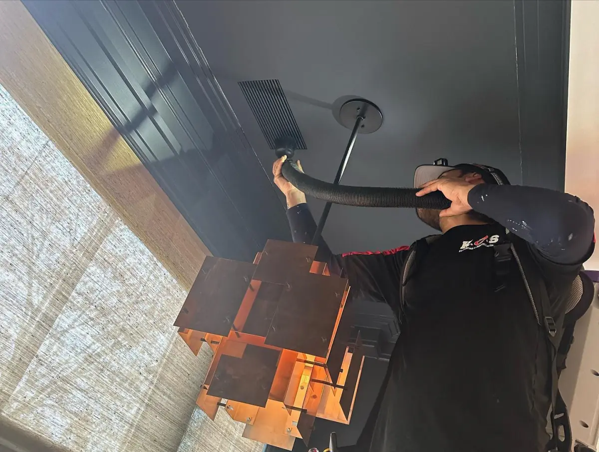 a man is cleaning a ceiling with a vacuum cleaner