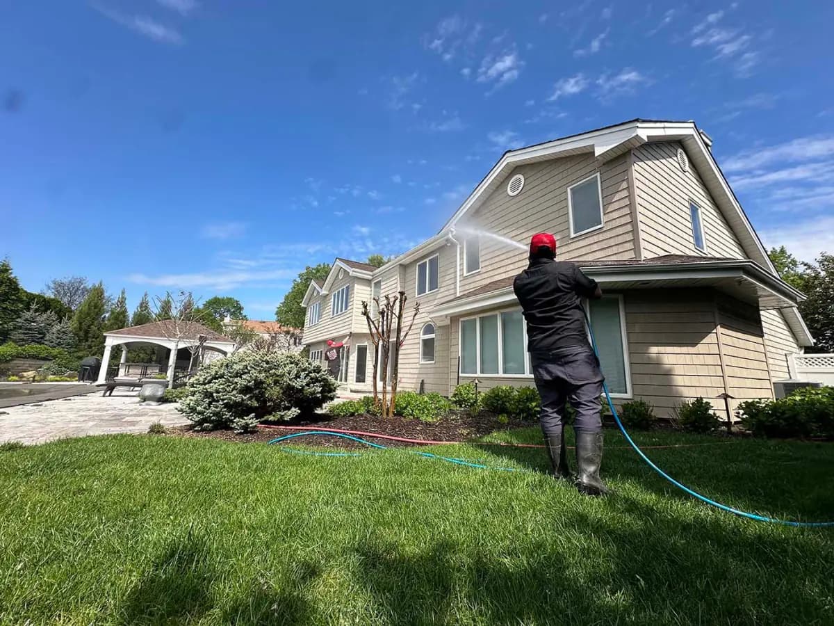 K.O.S. technician soft-washing the siding of a Long Island home