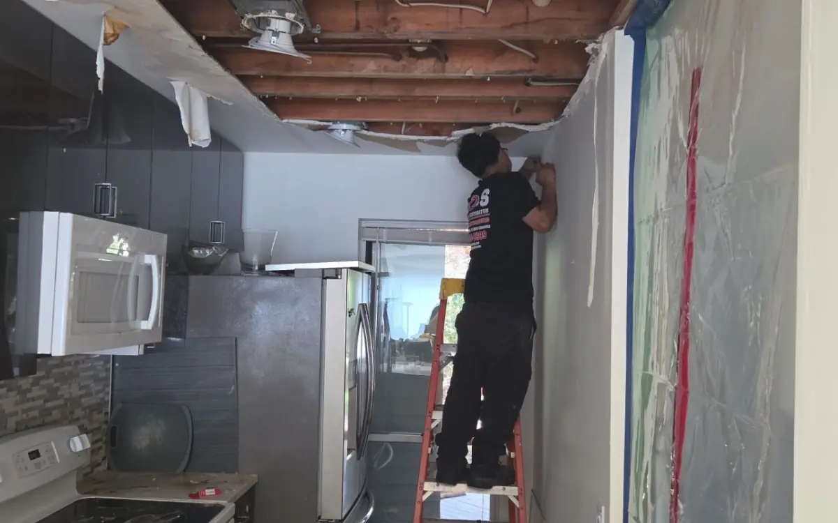 K.O.S. Restoration technician removing water-damaged ceiling in Westhampton Beach condominium kitchen