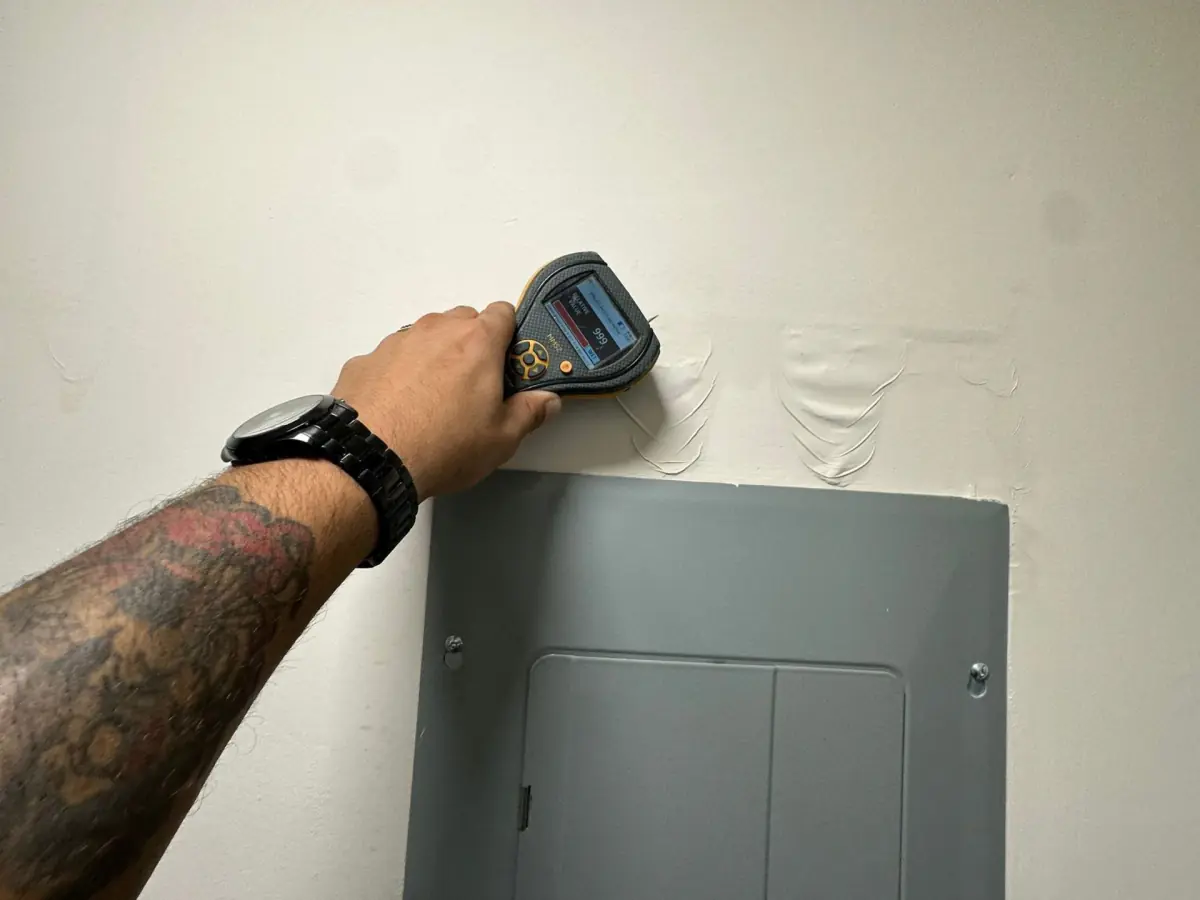 Moisture meter checking the wall beside the electrical panel