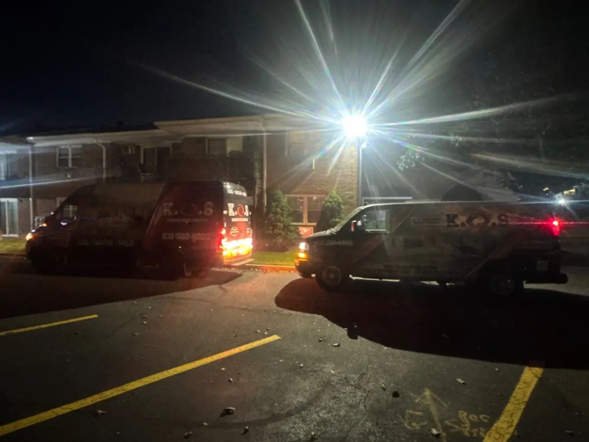 Two K.O.S. vans parked outside the condo complex at night