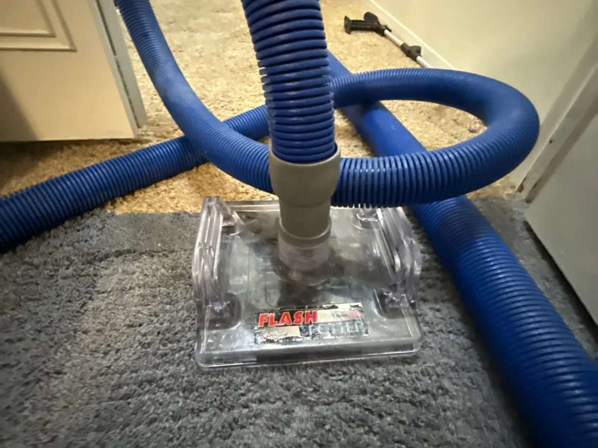 Clear weighted extraction tool on the carpet with the hose attached