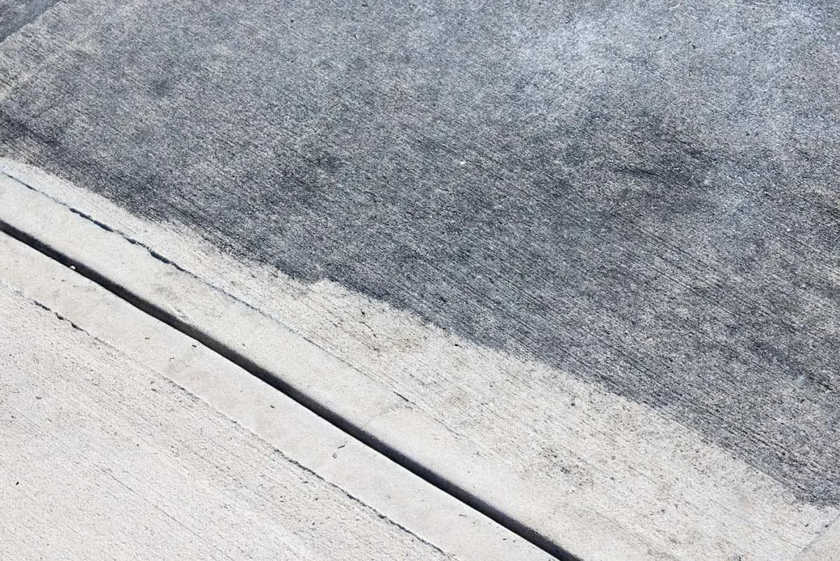A concrete driveway with visible back staining in Suffolk County NY