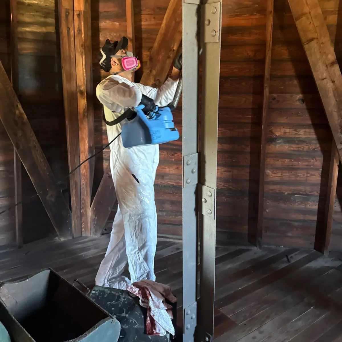 Technician applying disinfectant with a backpack sprayer inside the windmill
