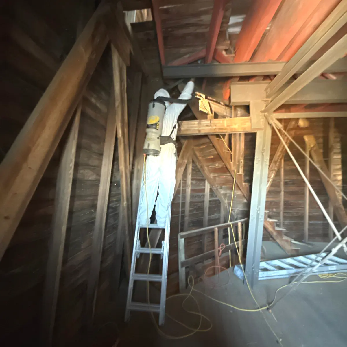 Technician on a ladder cleaning the windmill's upper beams
