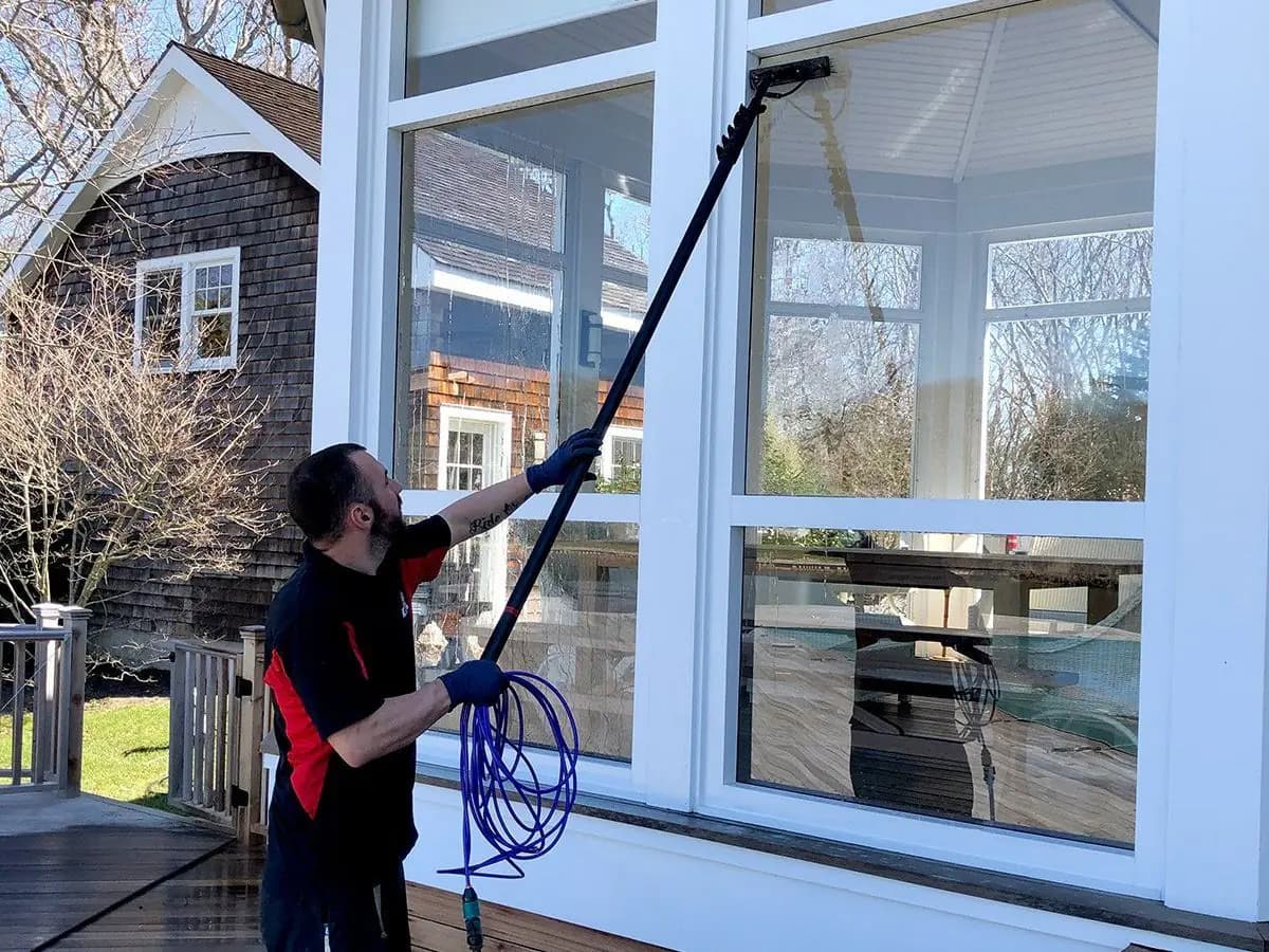 K.O.S. technician cleaning a sunroom's windows with a water-fed pole