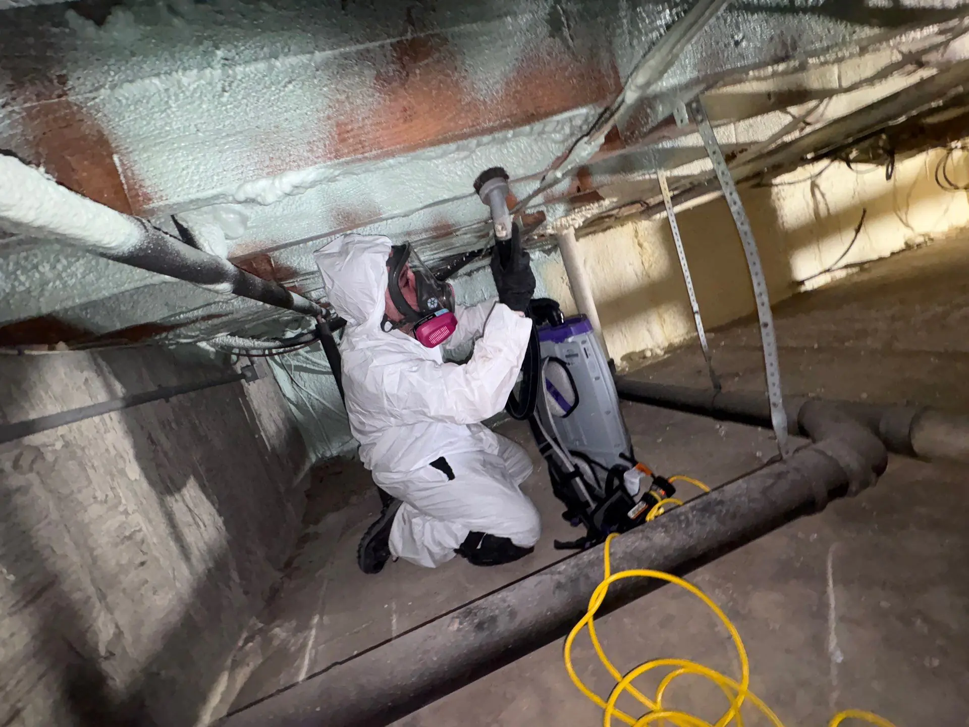 Handler in full PPE inside a contained crawlspace