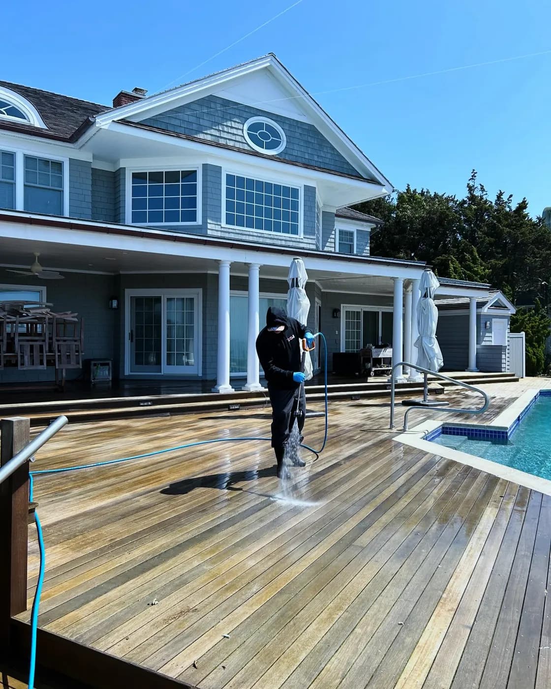 K.O.S. technician pressure-washing a wood pool deck