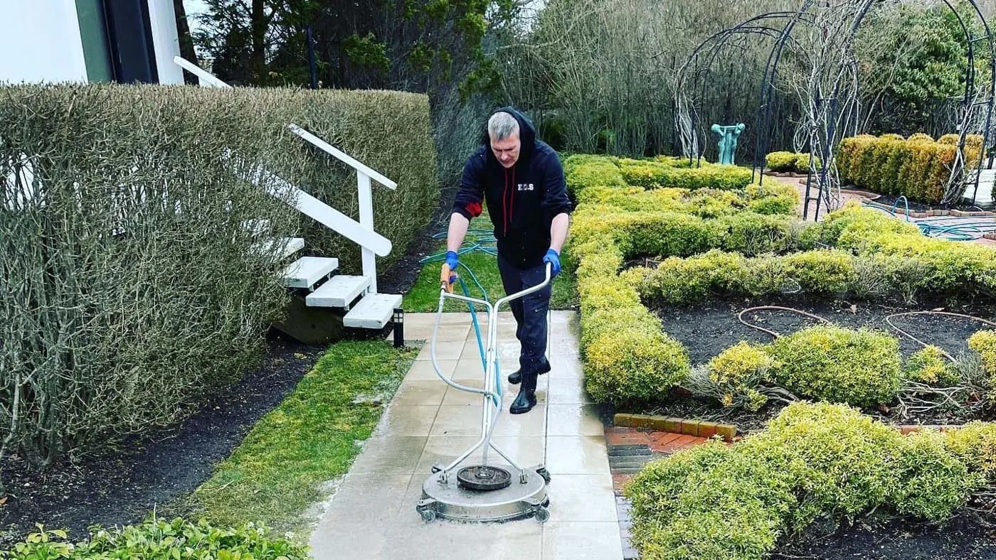 K.O.S. technician running a surface cleaner down a garden walkway