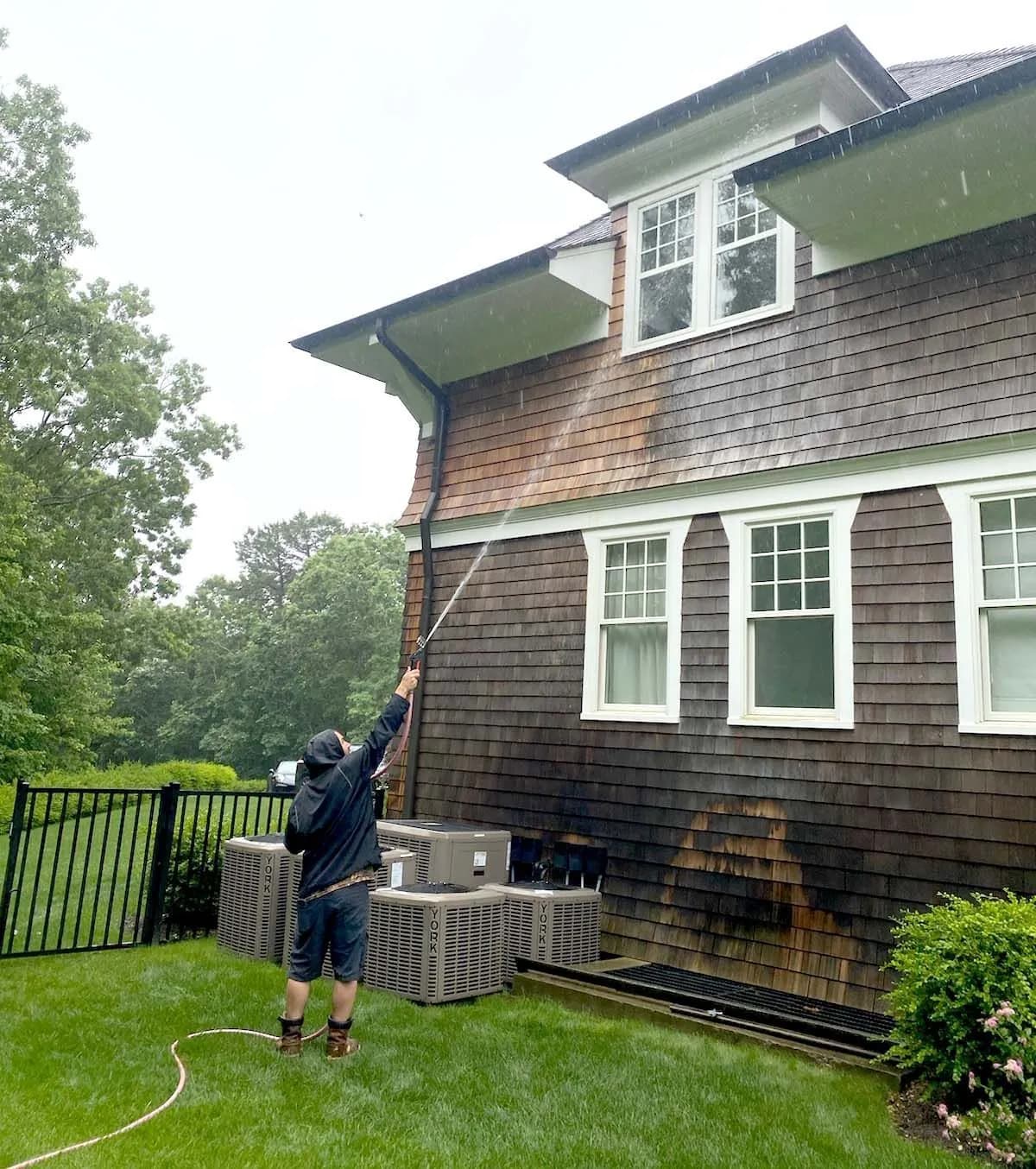 K.O.S. technician soft-washing the shingle siding of a two-story Long Island home