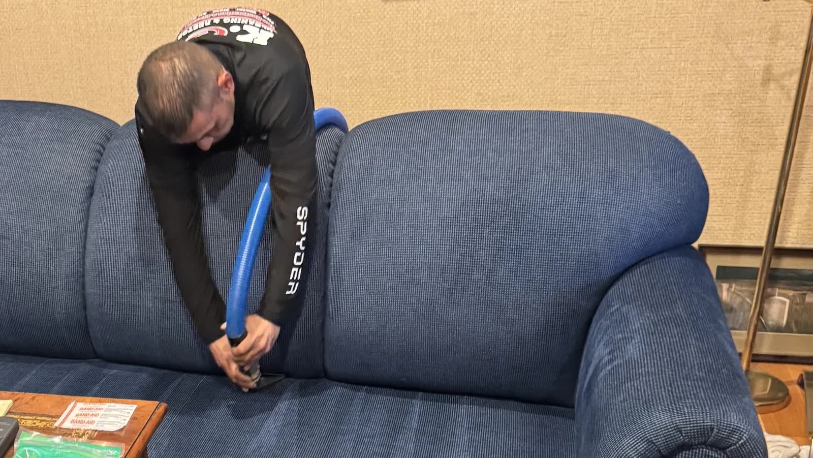 K.O.S. technician cleaning a fabric sofa with an upholstery extraction tool